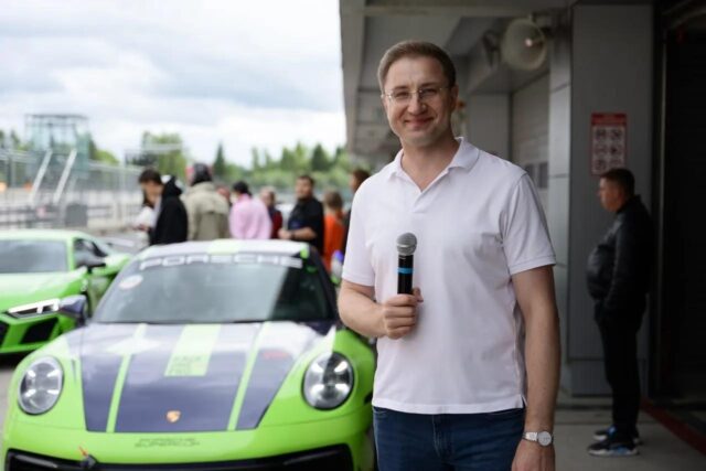Ведущий гонки Роман Акимов на фоне Porshe 911
